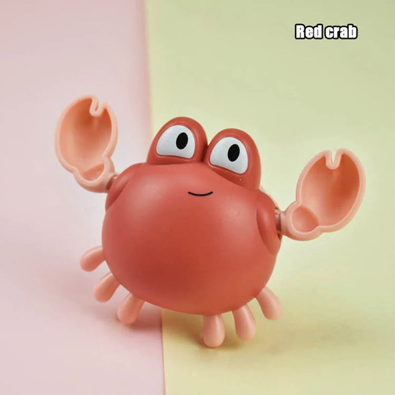 A small, pinkish-orange rubber toy of a red crab with large claws and smiling eyes.
