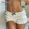 A woman wearing white ruffled tiered shorts with a black bow detail, shown from the back.