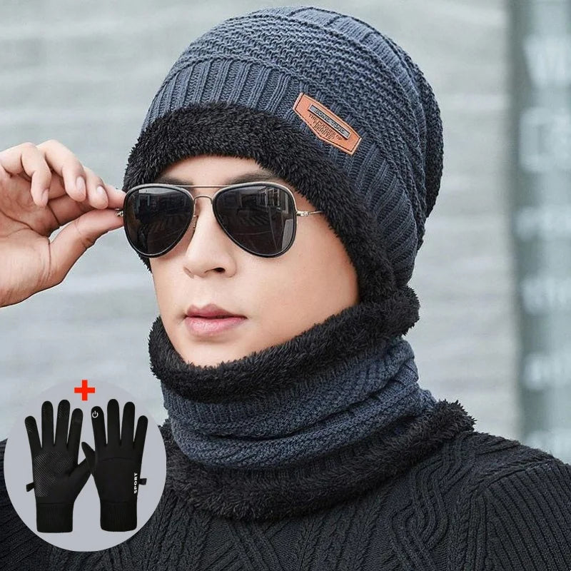 A model wears a dark gray knit beanie with a leather patch, sunglasses, and a matching scarf, with black gloves visible below