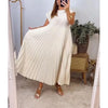 A woman wearing a long, cream-colored pleated midi dress standing in front of a mirror.