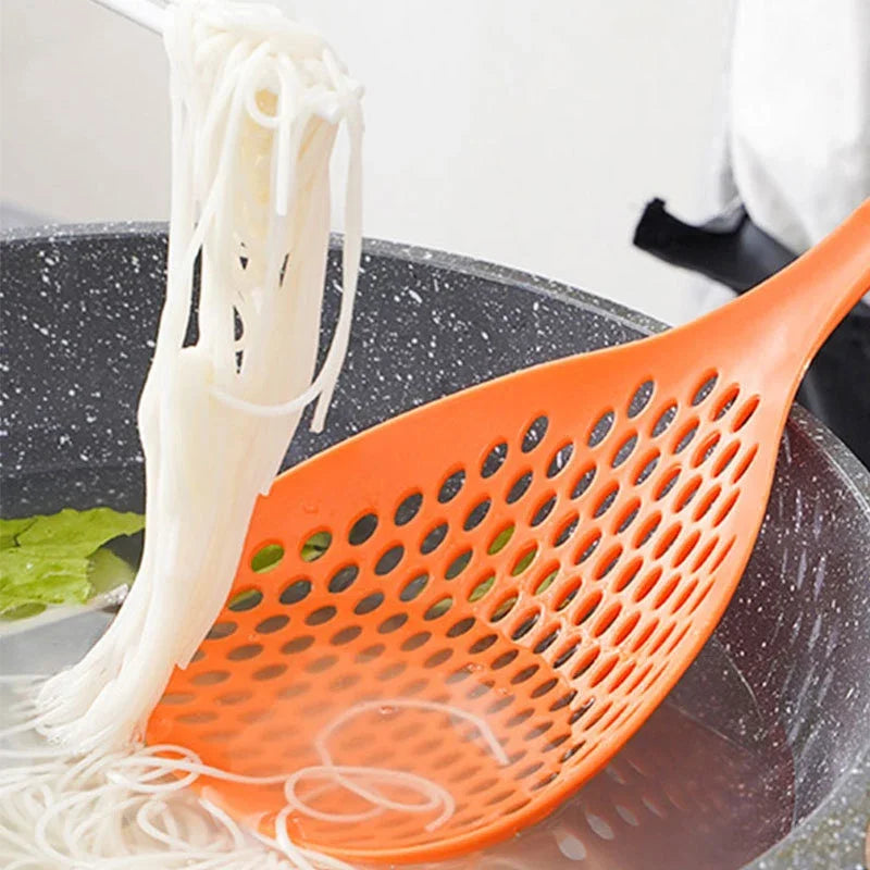 An orange kitchen strainer spoon is scooping white noodles or strands from a dark bowl.