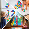 A child is building a colorful structure using magnetic tiles on a table, with other tiles and a large tile pattern visible.