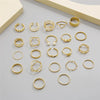 A collection of gold rings featuring various designs including hearts, geometric shapes, crosses, and pearl accents.