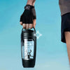 Eine Hand mit schwarzem Handschuh hält einen schwarzen, wiederaufladbaren, elektrischen Proteinshaker mit automatischem Mixer