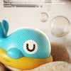 A yellow and blue musical light-up whale baby bath toy is shown resting on soft, brown fabric.
