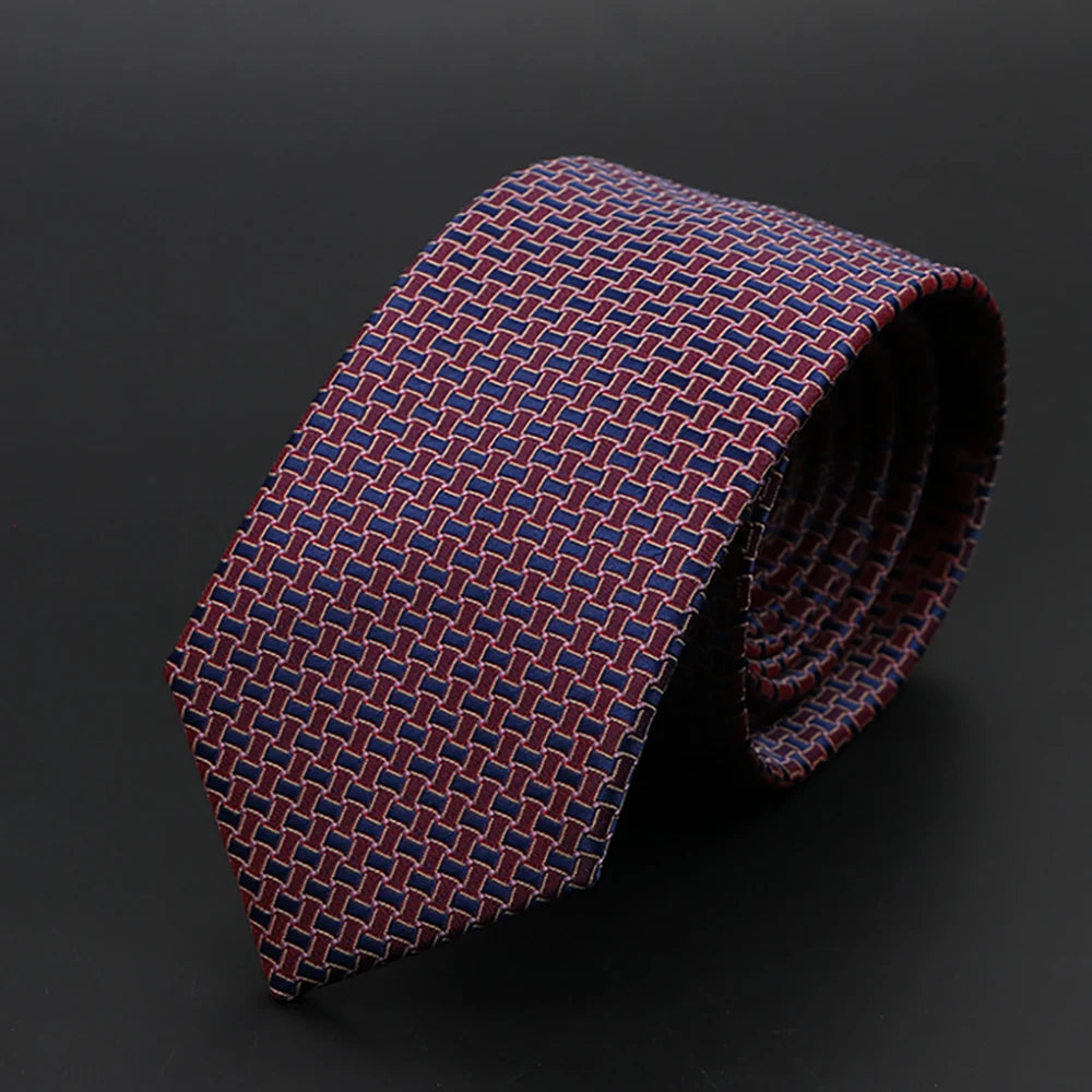 Primer plano de una corbata jacquard ajustada para hombre, color granate y azul marino, enrollada.