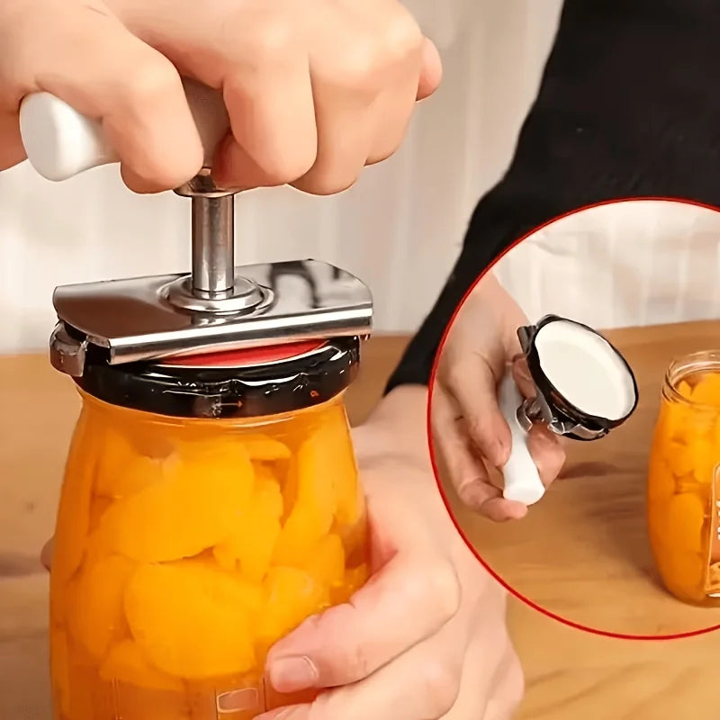 A hand is using a stainless steel manual tool to open an orange-colored glass jar.