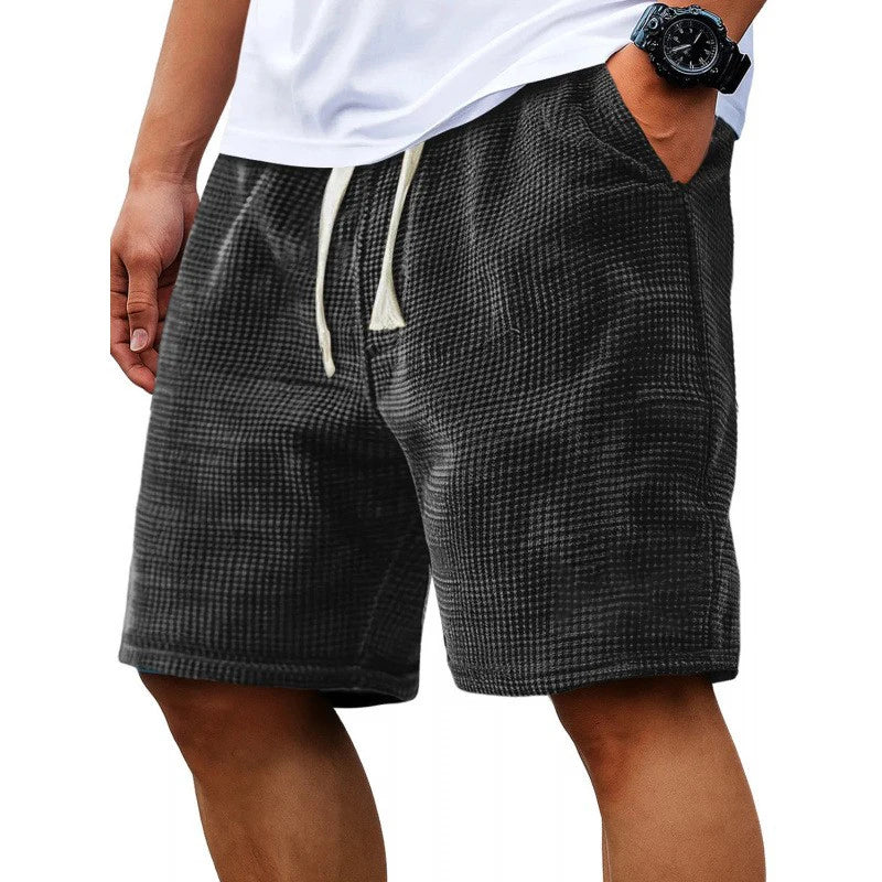 Short casual de textura waffle para hombre, en tejido negro, con cordón ajustable, usado por una persona.