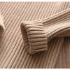 A close-up of a beige knit turtleneck sweater for kids, showing the ribbed texture and cuff detail.