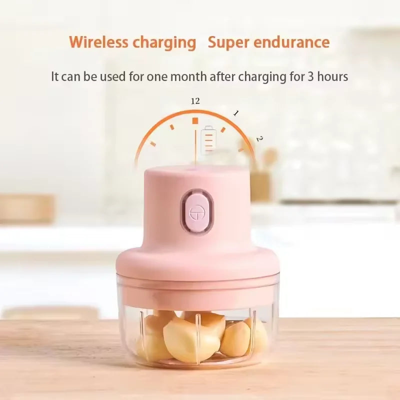 En rosa bærbar elektrisk foodprocessor med gjennomsiktig beholder på en treoverflate.