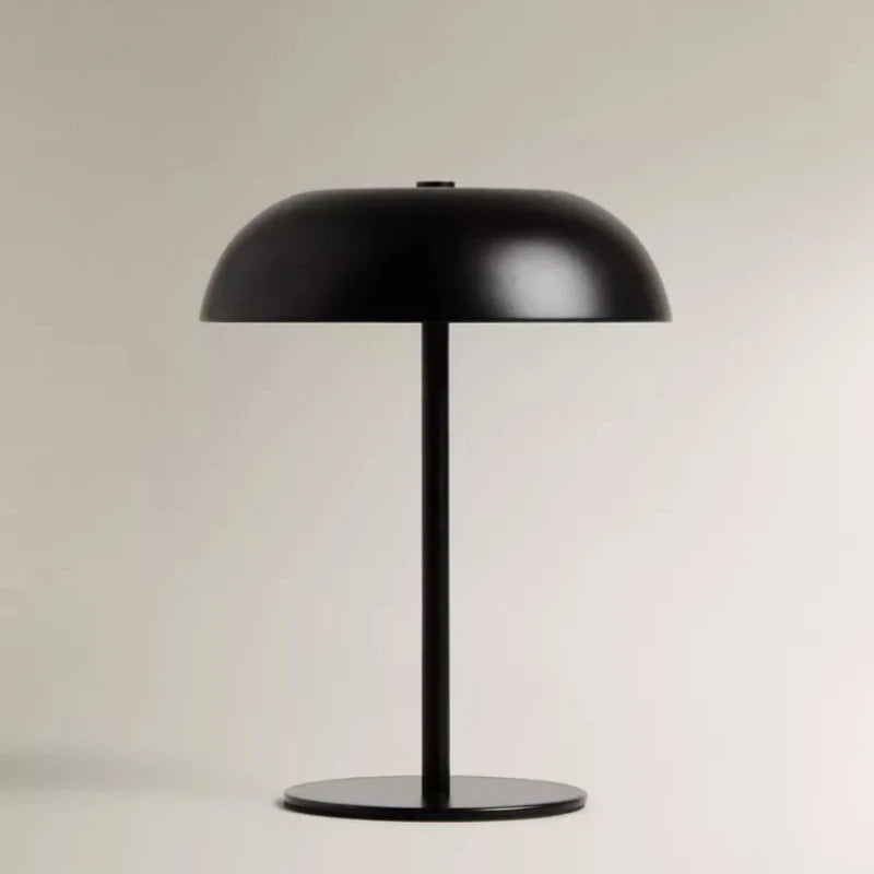 A black portable touch table lamp with a dome shade and a slender stand.