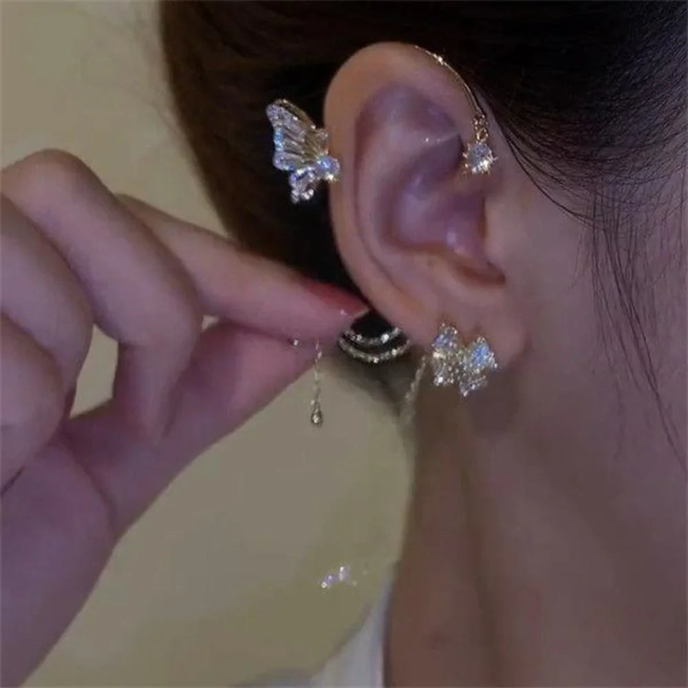 A close-up of a woman wearing butterfly zircon ear cuffs with gold tassels.