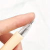 A hand holds a clear pen-style utility cutter with a sharp point for paper crafts and office use.