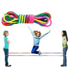 A colorful rainbow elastic jump rope is stretched across a line, with a girl jumping over it.