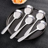 A set of five stainless steel serving spoons arranged on a dark plate.