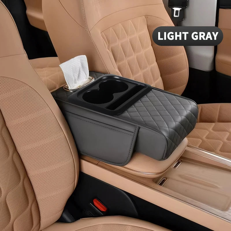 A light gray car center console organizer with a padded armrest and cup holder is shown in a beige car interior.