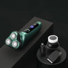 A close-up display of a green electric shaver with a floating head and LCD screen resting on a black surface.