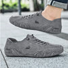 A gray leather slip-on loafer is shown on a foot, with the shoe resting on a concrete surface.