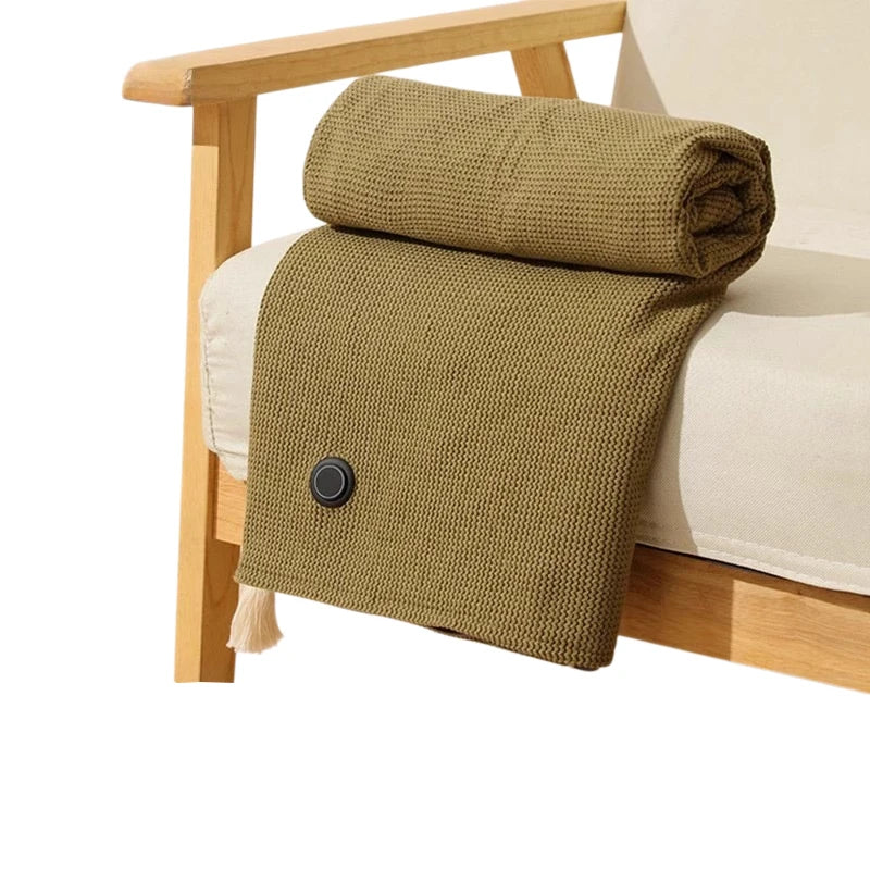 A textured olive green knitted shawl or blanket draped over a light-colored sofa.
