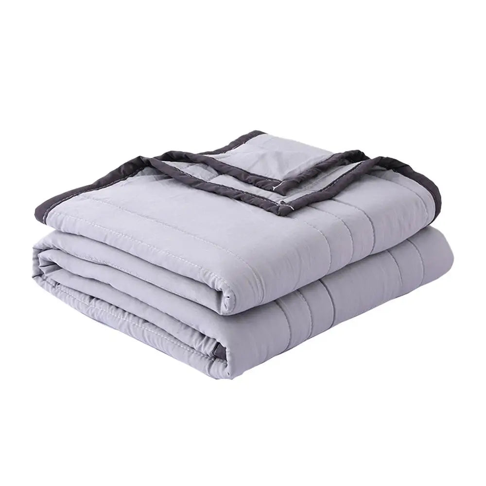 A stack of light gray breathable cooling throw blankets with dark trim.
