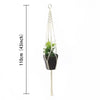 Macramé-plantekurv med hvit snor og grønn plante i svart potte, hengt opp i en løkke.