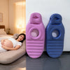 A pair of purple and blue inflatable maternity support pillows resting on a floor next to a woman lying on a couch.