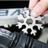 A hand is holding a silver 18-in-1 compact multi-tool with various tools, including a screwdriver and bottle opener.