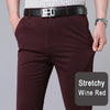 A close-up shot of a man wearing deep wine red stretch trousers and a black belt, showing the fit of the pants.
