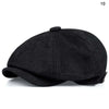 Black vintage retro newsboy cap with a folded brim shown from the side.