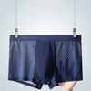 Navyblå herrmeshboxershorts hängande mot en ljusgrå bakgrund.