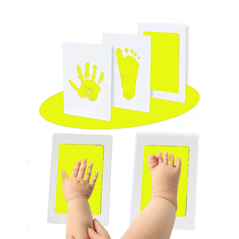 A set of yellow inkless baby handprint and footprint keepsakes displayed on white cards.