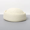 A beige straw pillbox sun hat with a wide brim shown against a gray background.