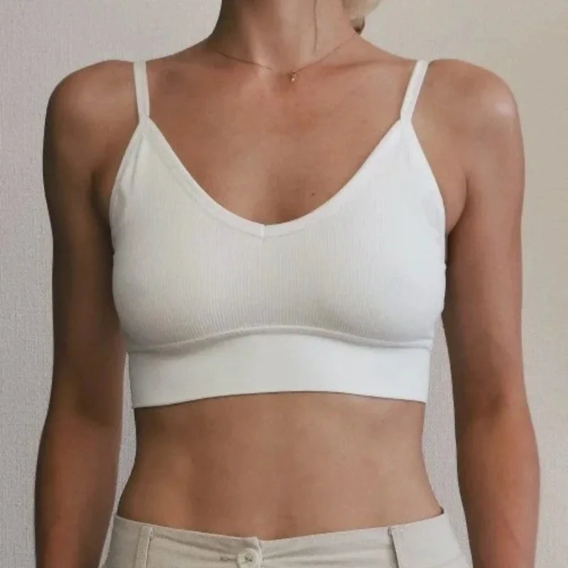 A model wearing a white seamless U-back bralette top and light colored pants.