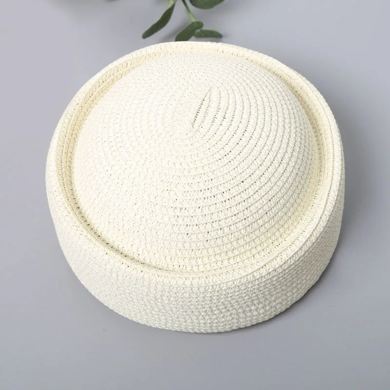 A round straw sun hat with a wide brim in a natural beige color, shown against a gray background.