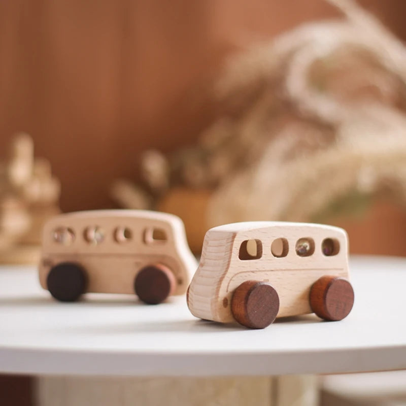 A light wooden hand-pushed cart toy for toddlers resting on a white surface with blurred natural elements in the background.