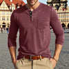A man wearing a maroon long-sleeve casual shirt with a chest pocket and tan pants outdoors.