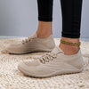 Ein Paar beiger, atmungsaktiver, minimalistische Wanderschuhe auf einer gewebten Matte.