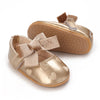 A pair of gold glitter baby first walker shoes with suede straps and a matching soft non-slip sole.