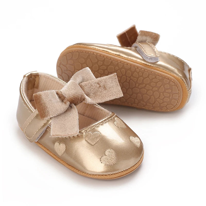 A pair of gold glitter baby first walker shoes with suede straps and a matching soft non-slip sole.