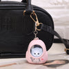 A pink bear-shaped nightlight keychain with an astronaut charm hanging from a black leather bag strap.