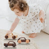 A young girl is playing with several hand-pushed wooden cart toys on a light-colored surface.