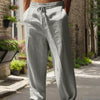 Hombre con pantalones casuales anchos gris claro de pie en una acera.