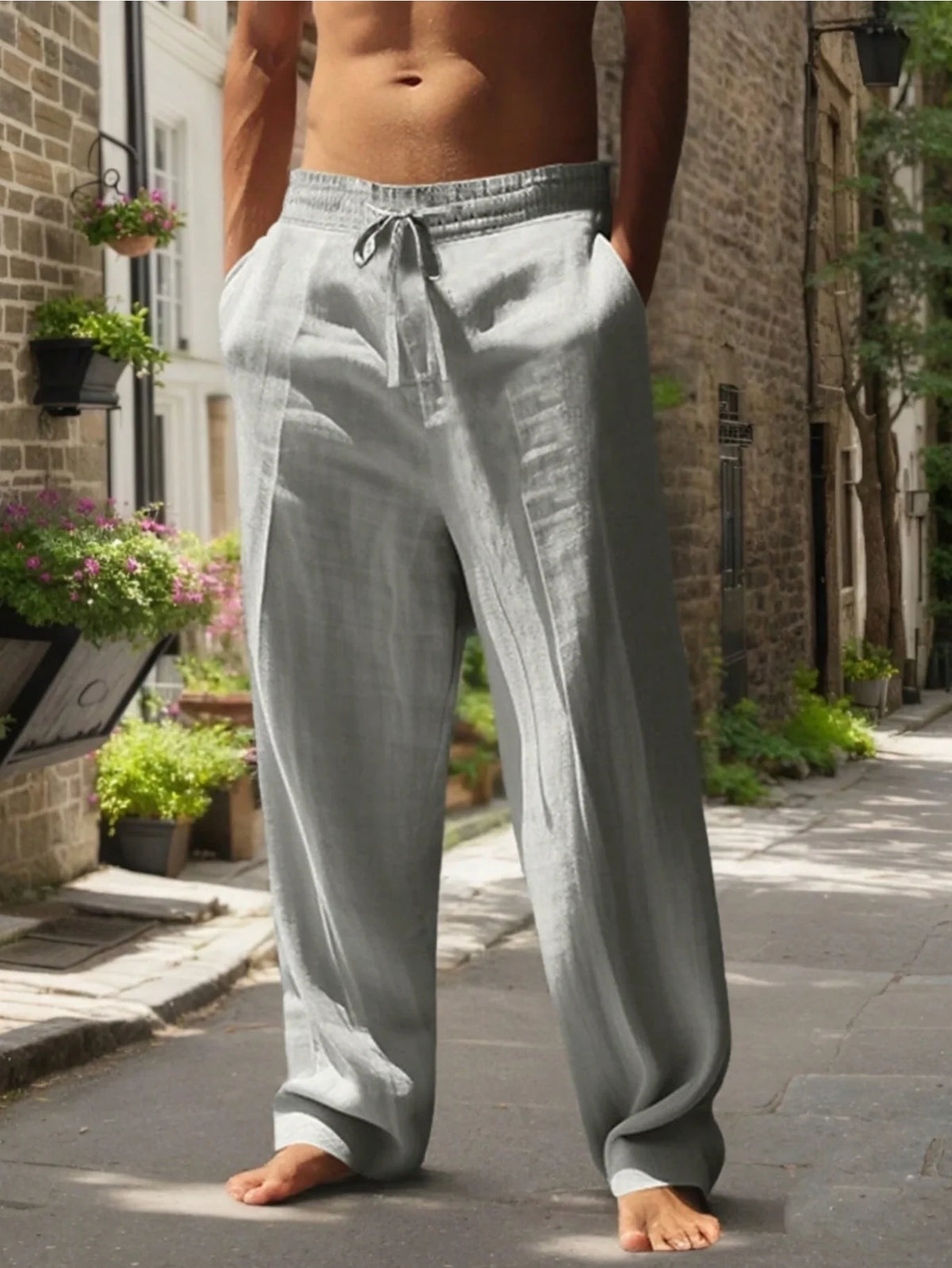 Un hombre con pantalones casuales holgados gris claro de pie en una acera.