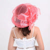 A pink ruffled organza sun hat with a wide brim is shown on a model's head.