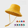 A yellow wide-brim bucket hat with a woven texture and tan leather cord strap.