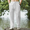 A pair of men's white cotton linen casual jogger pants being held by a person outdoors.