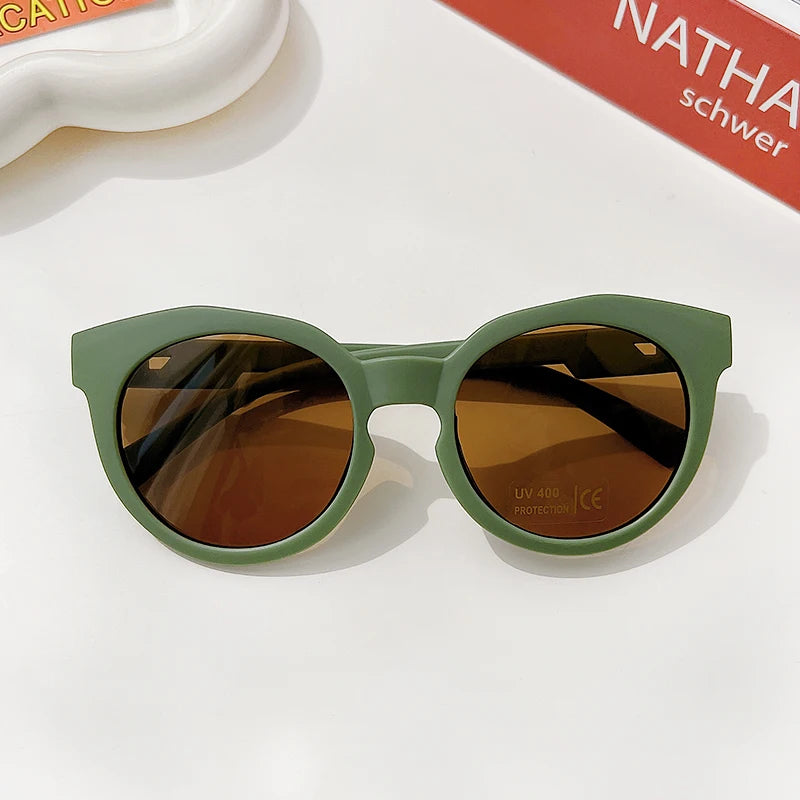 Olive green polarized sunglasses with brown lenses resting on a white surface.
