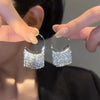 Close-up of a person wearing gold geometric tassel drop earrings
