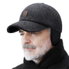 A man wearing a dark gray woolen knit baseball cap with earflaps and a black scarf.