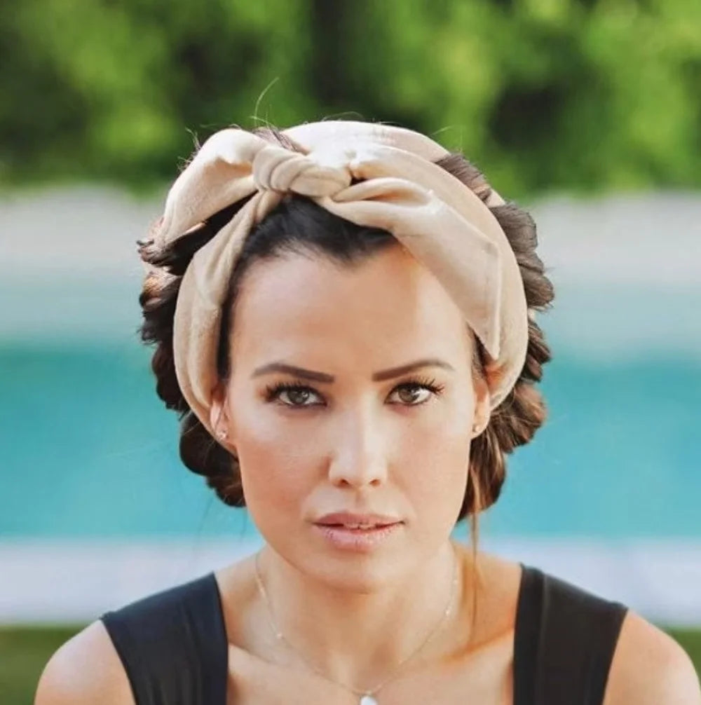 A woman wearing a beige heatless curling rod headband with dark hair, outdoors.